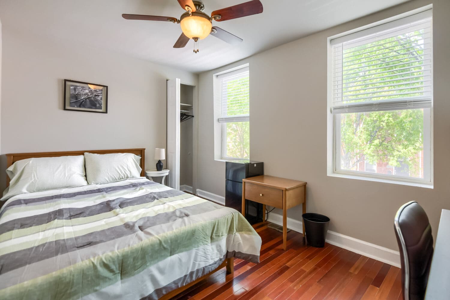 Modern bedroom with exposed brick accent wall, wall-mounted TV, and hardwood floors